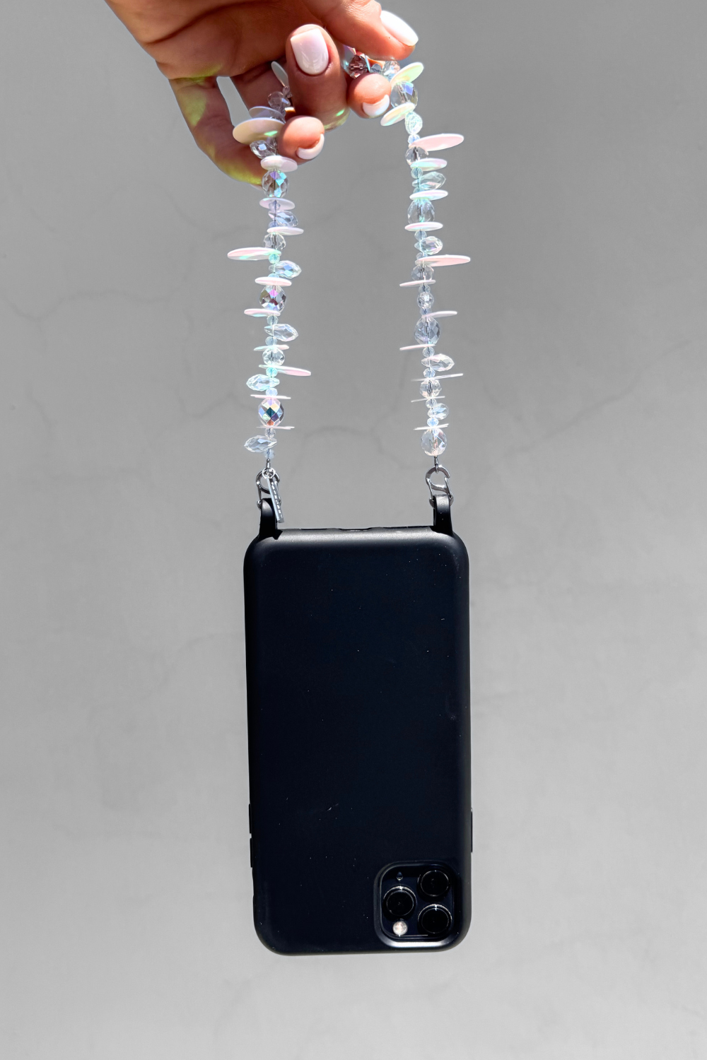 MIRAGE crystal phone charm worn on a black phone case with stainless steel clasps