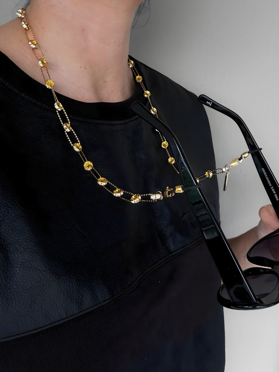 Woman wearing gold Swarovski crystal eyewear chain with black sunglasses