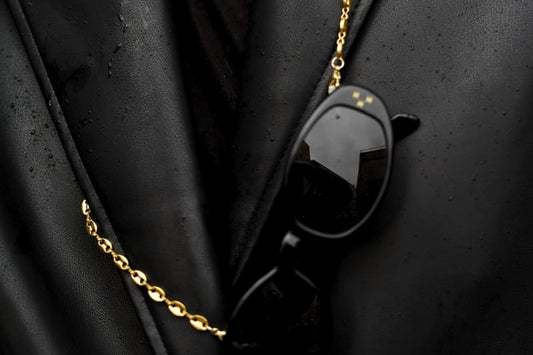 A gold eyewear chain on a black leather blazer.