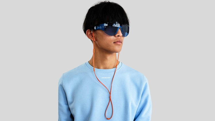 Man wearing vintage designer sunglasses paired with an orange eyewear cord showcasing it's distinct design.