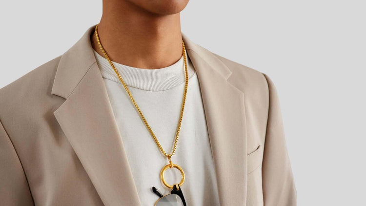 Model wearing gold eyewear lanyard holding a pair of sunglasses, showcasing it's minimalist aesthetic and functionality.