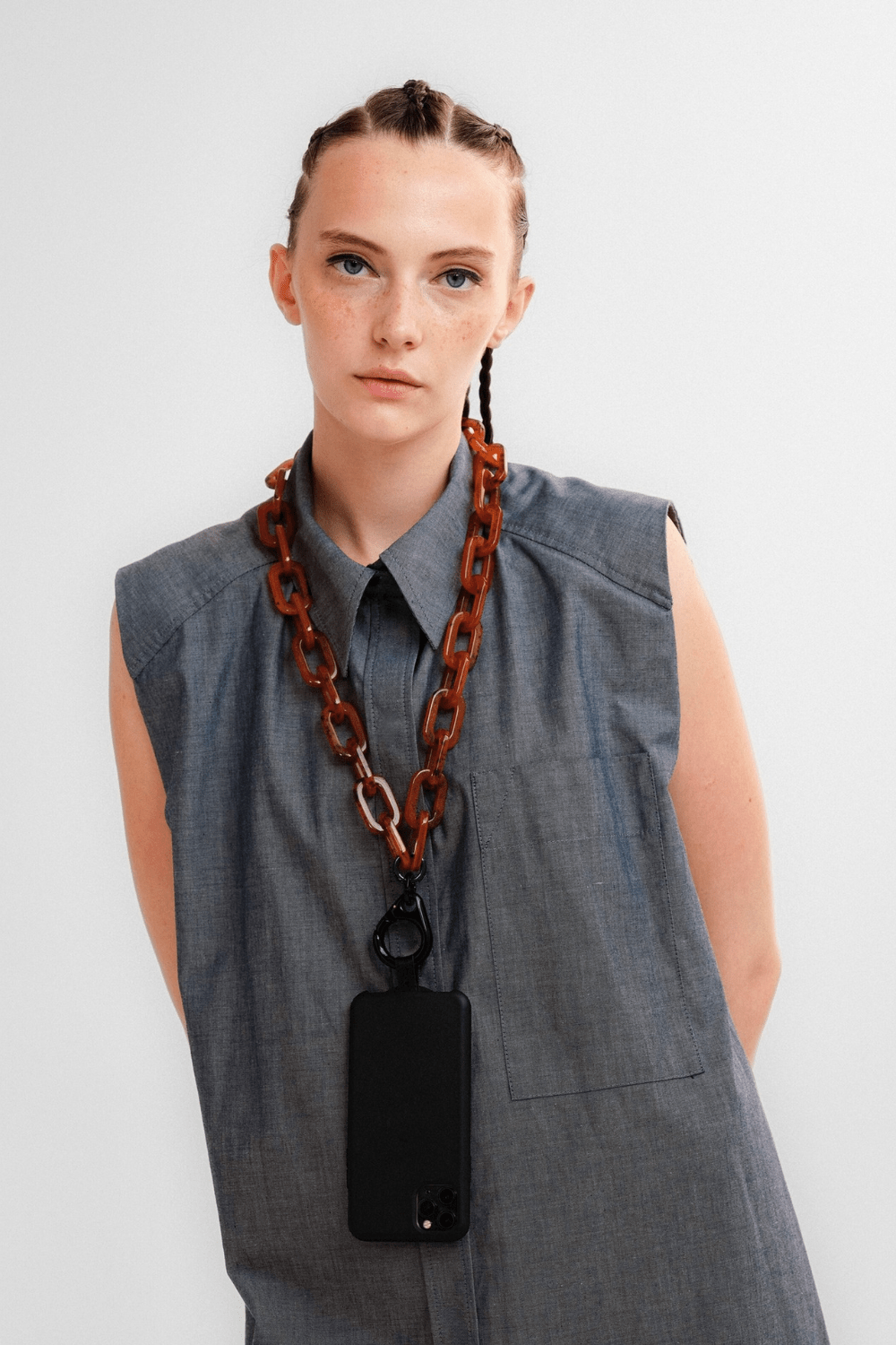 A woman wearing the Boldly Phone Chain with a black clasp ring holding a mobile phone.