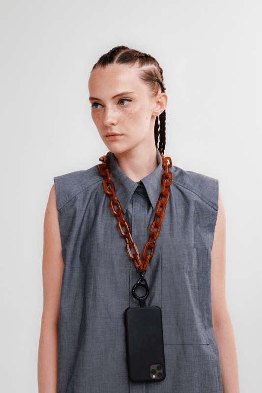 Model wearing the BOLDLY Chunky Tortoise-Shell Phone Chain as a lanyard/necklace against a gray top.