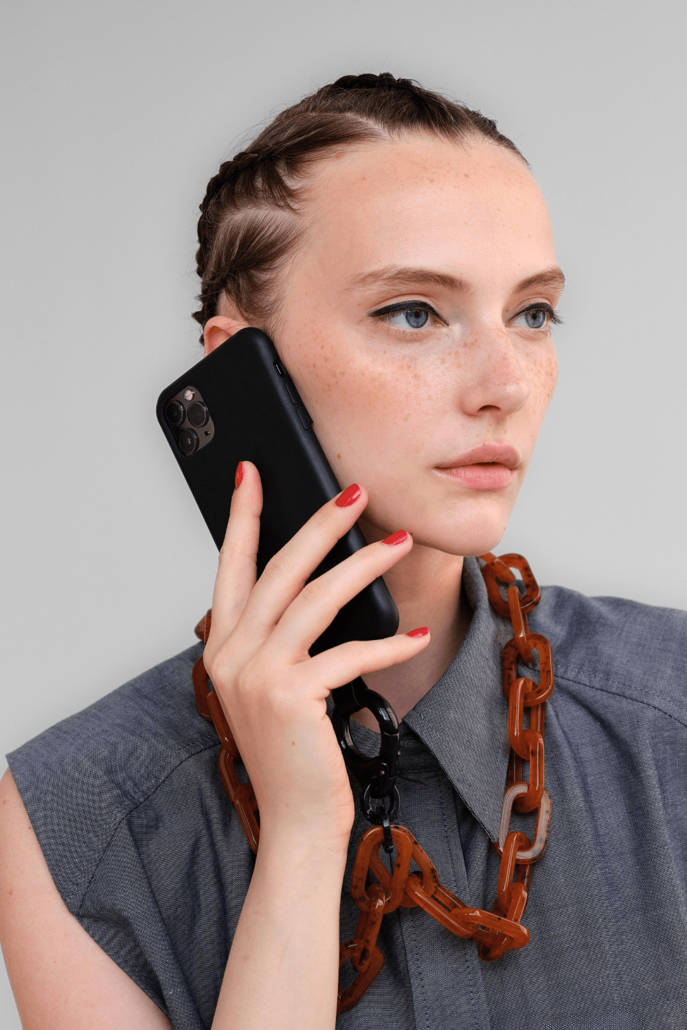Woman holding a black phone wearing the BOLDLY Tortoise-Shell Phone Chain.