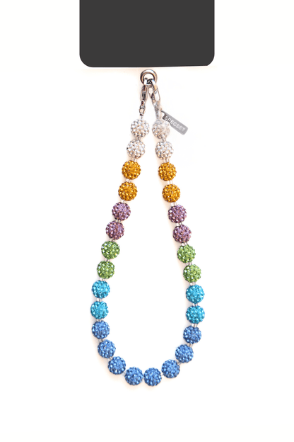 A black smartphone case attached to a multicolored beaded wrist strap. The strap features sparkling beads in shades of blue, green, purple, gold, and silver. The phone is securely attached to the strap with metal clasps.