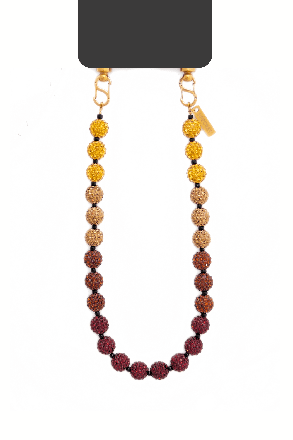 A stylish beaded phone wrist strap in an ombre color pattern, transitioning from gold to brown to deep red. The strap is connected to a phone with gold-toned metal clasps and a small branded tag. The beads are encrusted with rhinestones, giving the strap a shimmering effect.