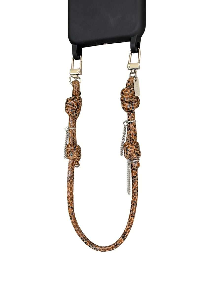 A brown leather phone strap with knotted details and silver metal hardware, attached to a black phone case against a white background.
