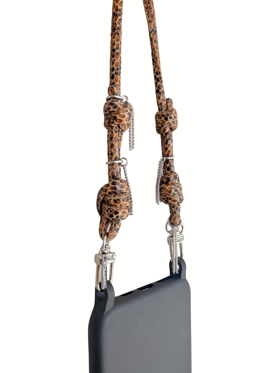 A black smartphone with a brown leather strap attached by silver metal clips, close-up.