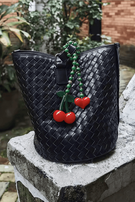 Cherrie bag charm with green gemstone beads, red heart, and a cute cherry - on a black handbag.