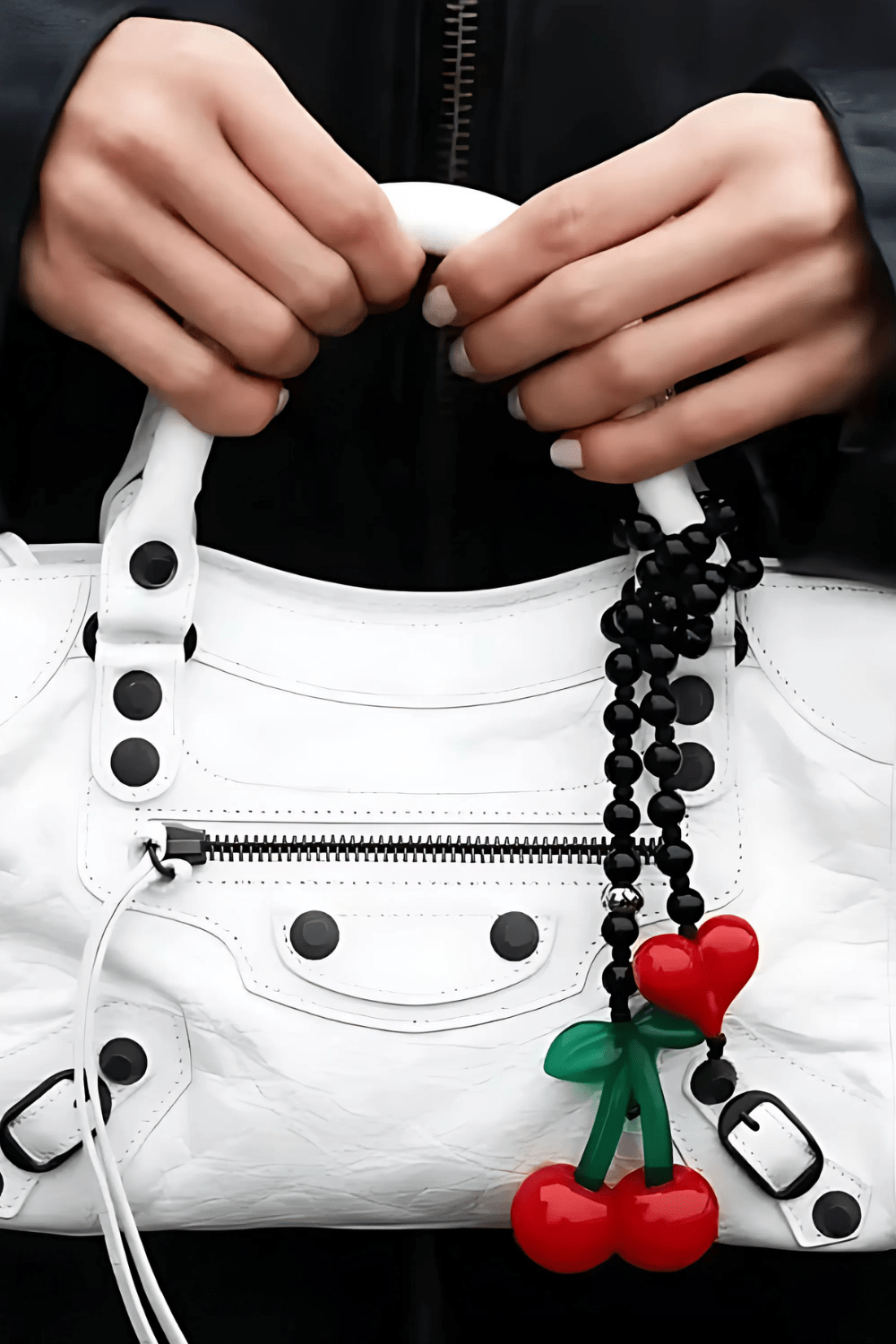 Cherrie bag charm with black gemstone beads, red heart, and a cute cherry - on a white handbag.