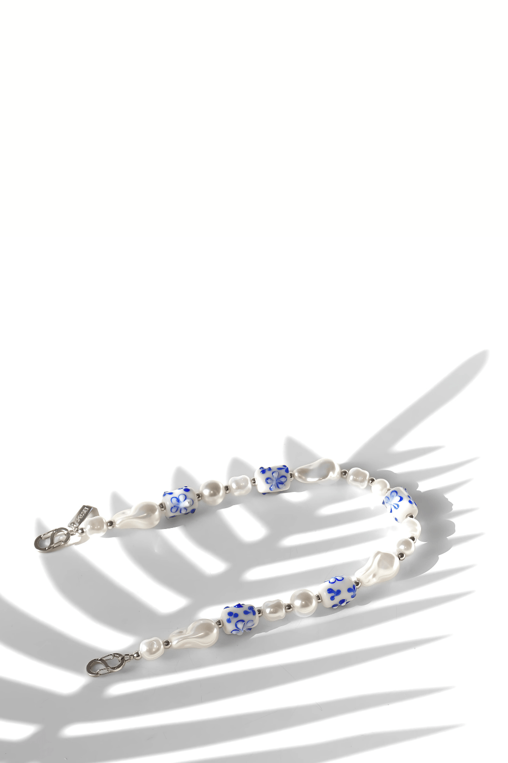 Side view of the strap focusing on the intricate floral patterns on the ceramic beads and the shimmer of the pearls.