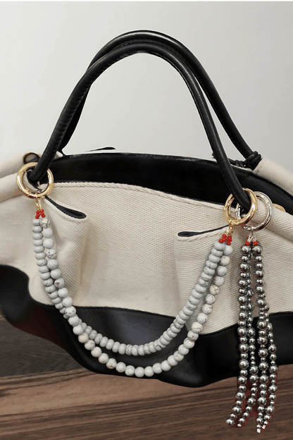 Black handbag with a beaded keychain attached on a wooden surface