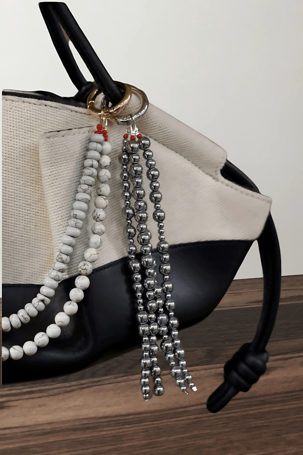 Classic Drop Bag Charm featuring grey pearls and a silver ring clasp, with a keychain hanging from a handbag on a wooden surface.