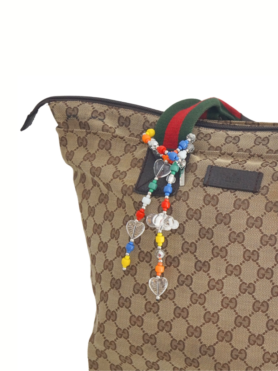Colorful beaded bag charm wrapped on a designer's handbag handle.