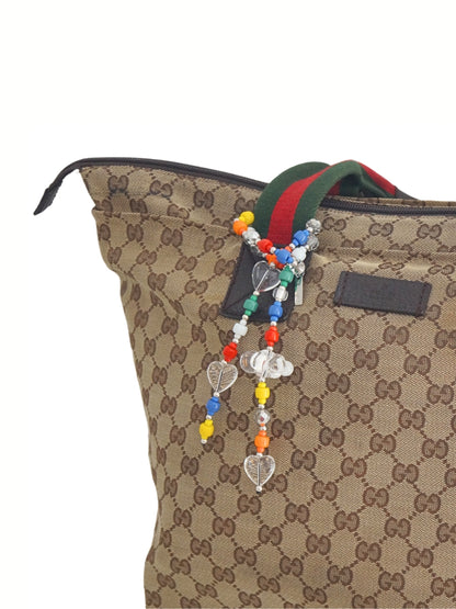 Colorful beaded bag charm wrapped on a designer's handbag handle.
