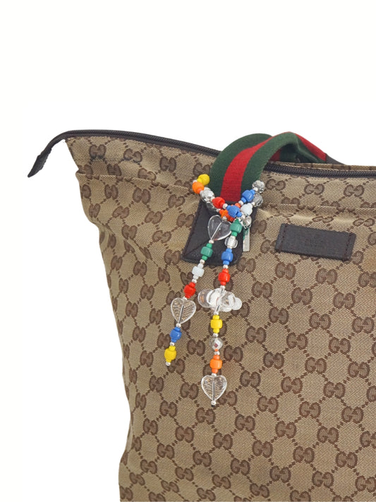 Colorful beaded bag charm wrapped on a designer's handbag handle.