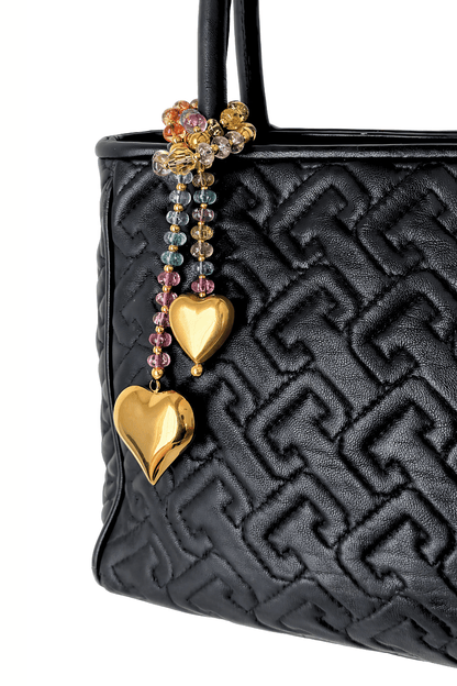 Colorful Swarovski crystal bag charm  
with gold hearts on a black handbag.