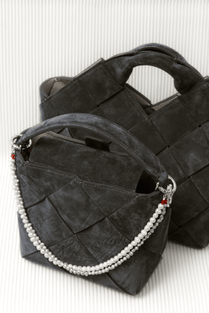 Close-up of a black handbag adorned with a two-layered bag charm of freshwater pearls on a white chair