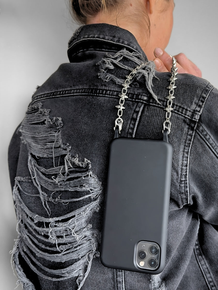 Person wearing a black phone case with FINE CUT phone chain on a gray background.