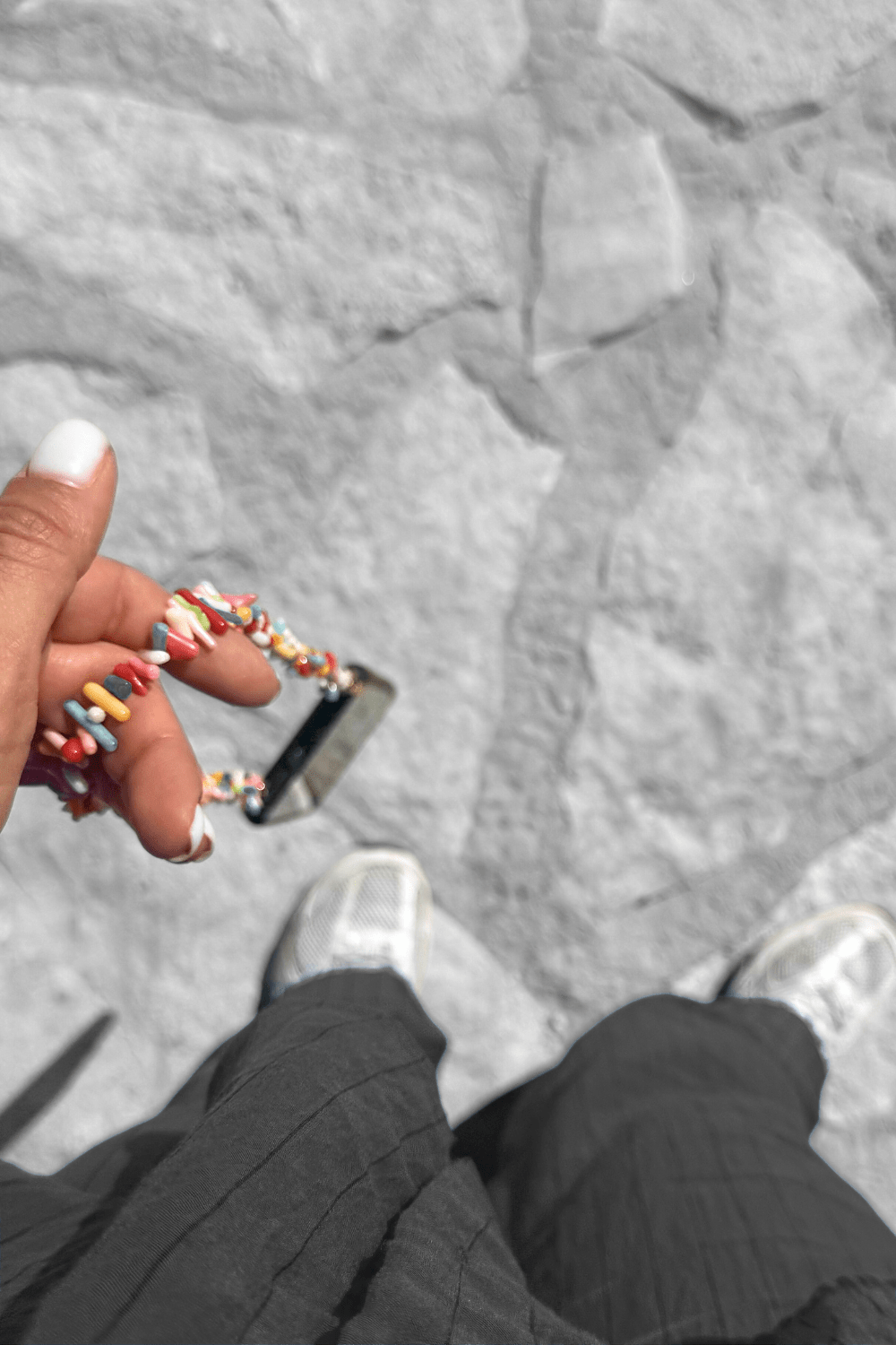 Person wearing the Free Spirit phone chain holding a phone with a gray textured background.