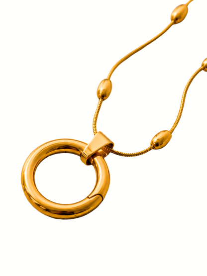 Gold-tone ring pendant necklace with a thin beaded chain on a plain white background.