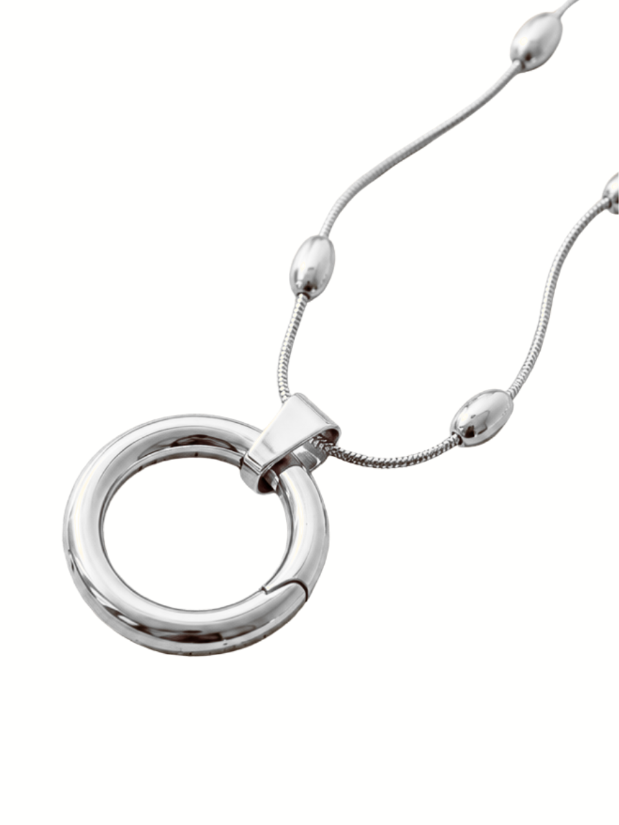 A polished silver-tone ring pendant necklace with a matching snake chain and small bead accents, shown on a plain white background.