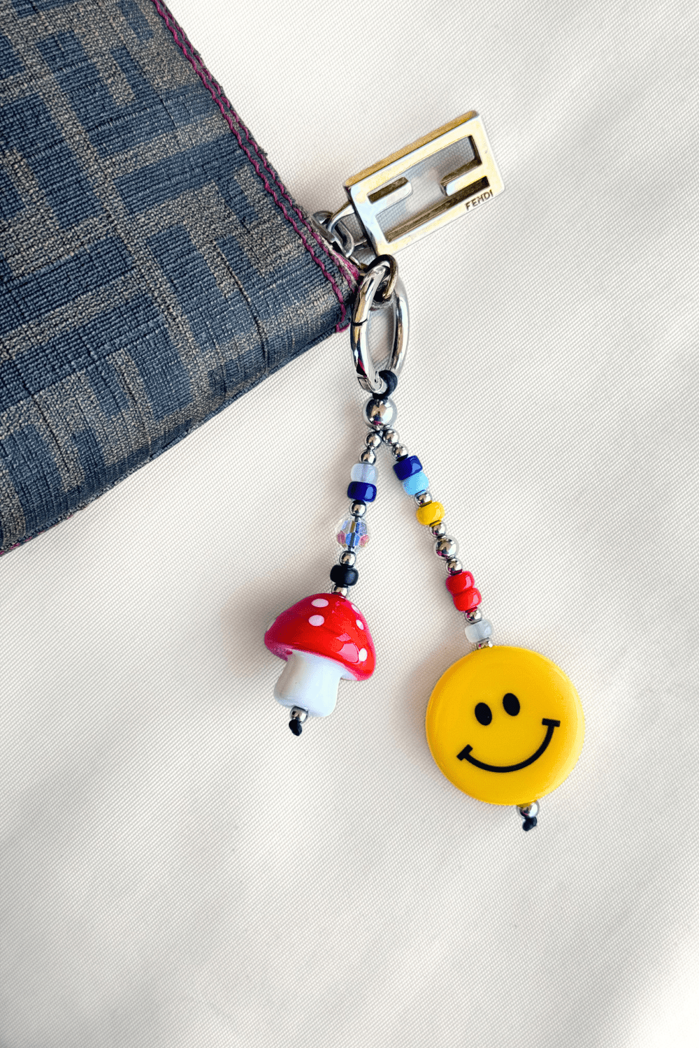 Keychain with mushroom and smiley face charm on a white background