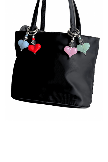 Black handbag with colorful heart-shaped charms on a white background
