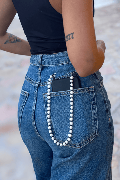 Woman wearing jeans, showing the Her Heritage Pearl Chain, securing a phone in the back pocket.