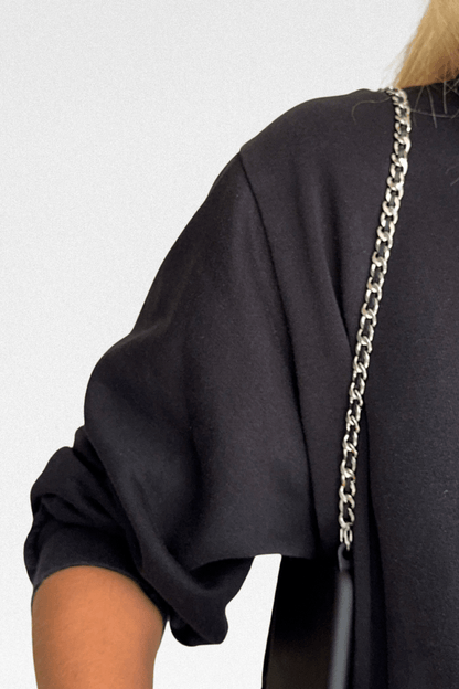 Person wearing a black outfit with the Iconic Phone Chain detail on a plain background.