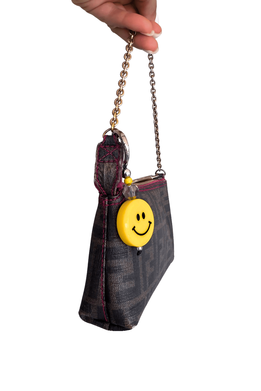 Handbag with a smiley face charm held by a hand on a white background