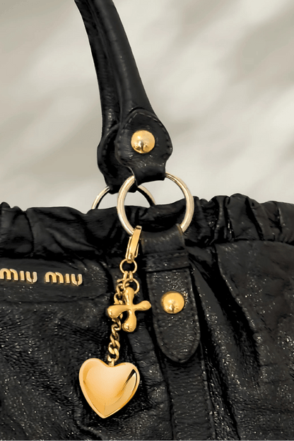 Luxury custom charm with gold heart pendant on a designer black tote bag.