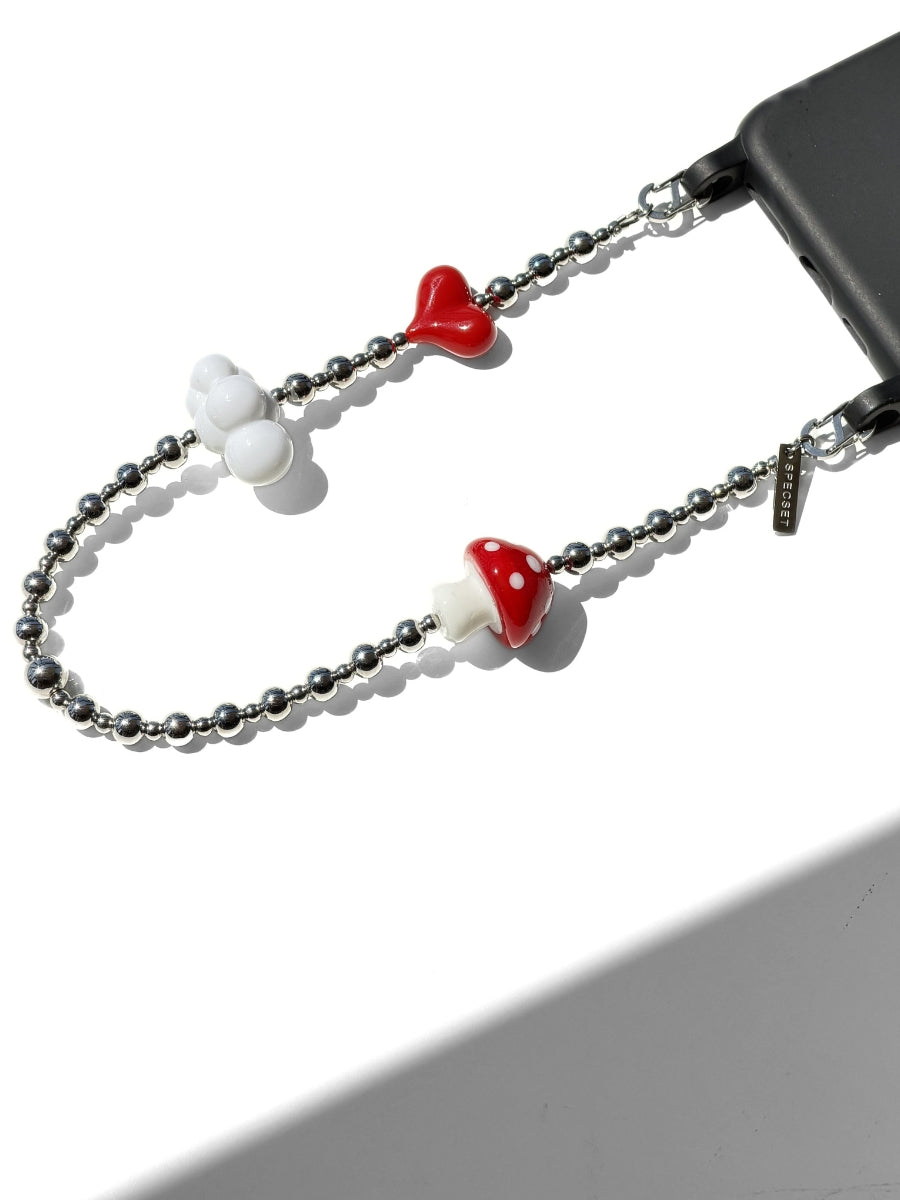 A silver beaded phone strap with decorative charms, including two red and white mushroom caps and a white cloud-shaped charm, shown attached to a black smartphone on a white background.