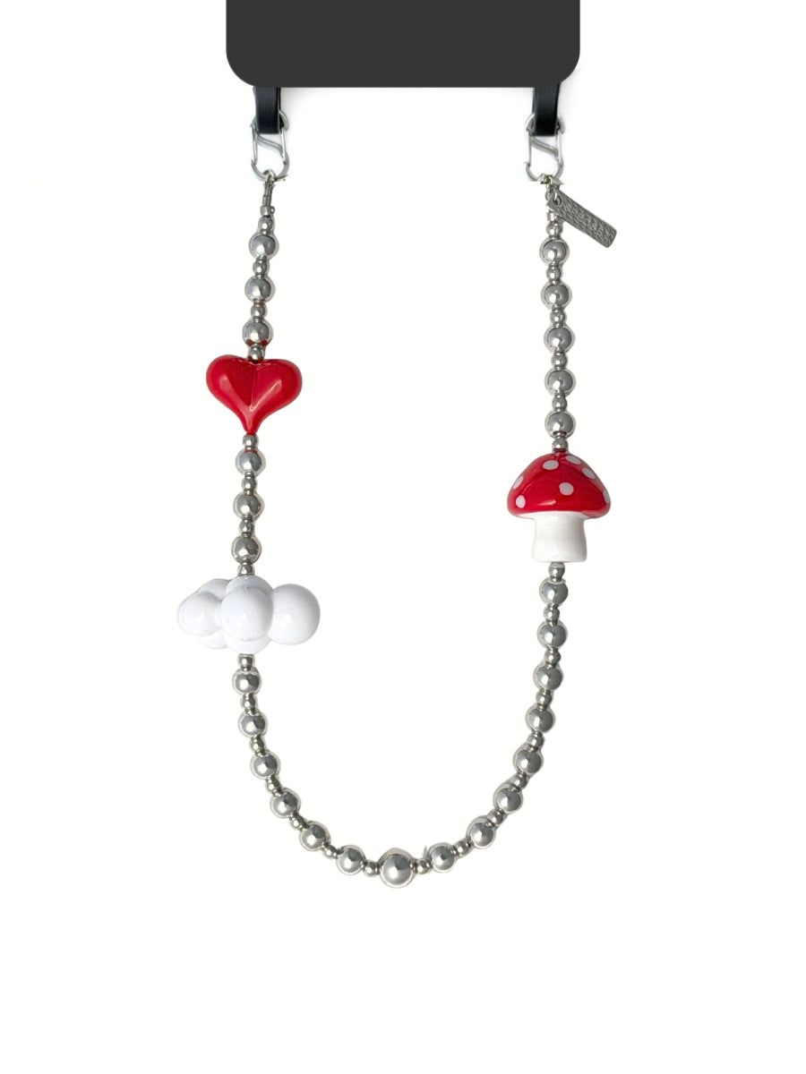 A silver beaded necklace featuring a glossy red heart, a red and white mushroom charm, and a white cloud charm, displayed on a black card hanger against a white background.