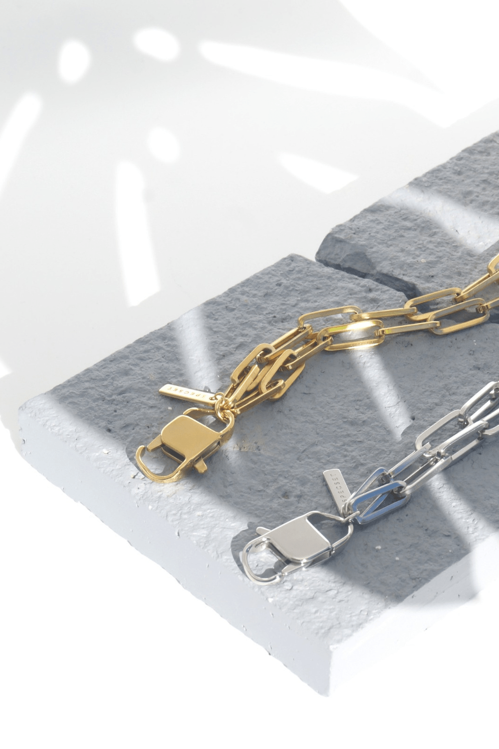 Gold and silver phone chain lanyards on a gray stone surface