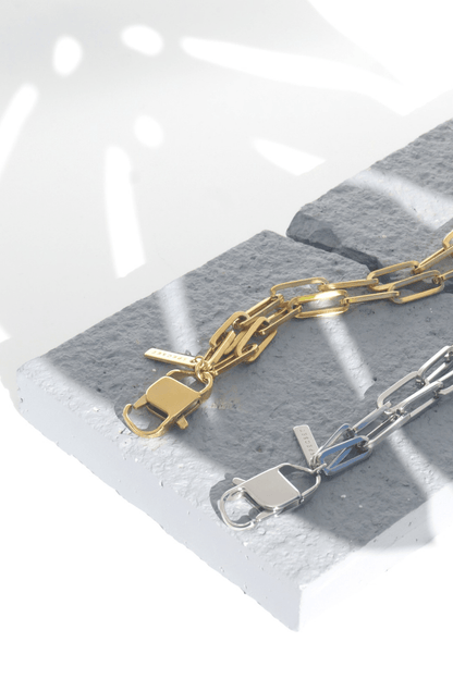 Gold and silver phone chain lanyards on a gray stone surface