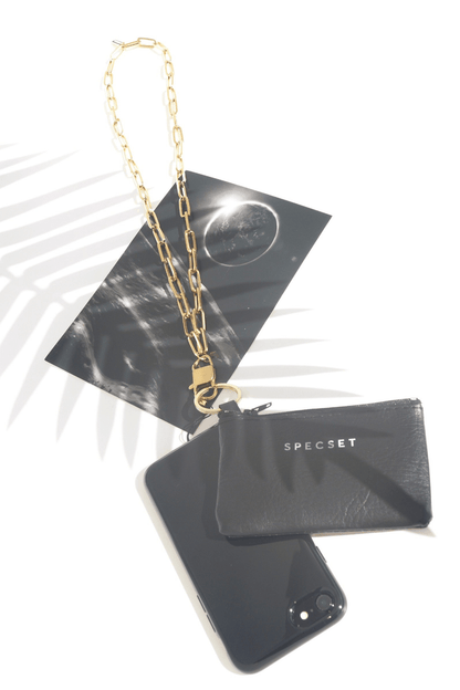 Black phone case with gold chain, black pouch, and 'SPECSET' branding on a white background.