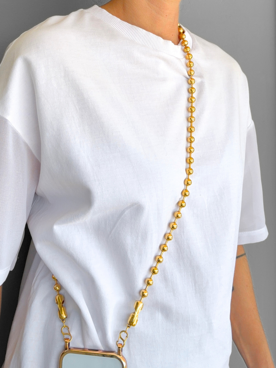 Play Call gold crossbody ball chain phone strap styled hands-free on a model.