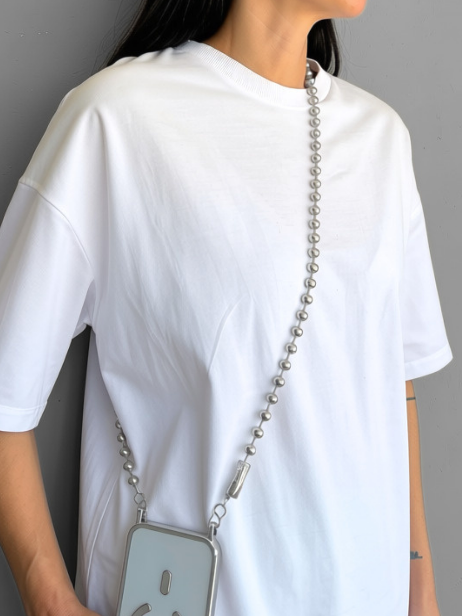 Play Call silver crossbody ball chain phone strap worn across the body over a white t-shirt.