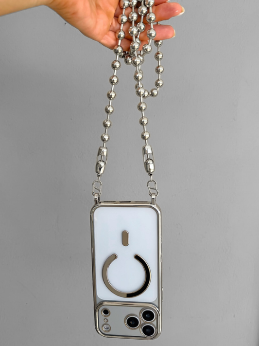 A silver metal phone case with a long beaded chain strap, held by a hand against a plain gray background. The phone case has a white back cover with a circular cutout design.