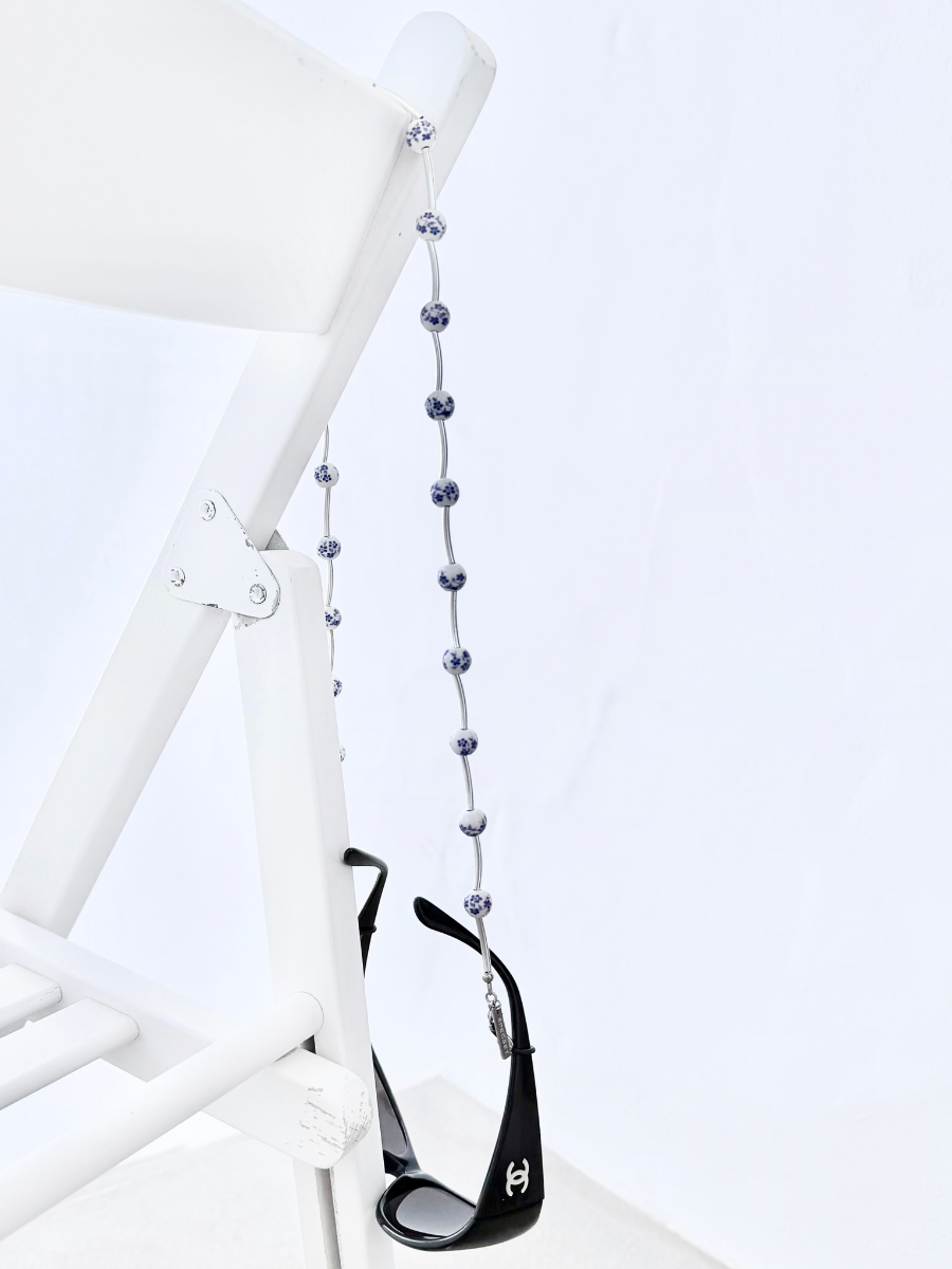 Pure Bloom handcrafted eyewear chain featuring silver bars and blue-and-white floral ceramic beads.