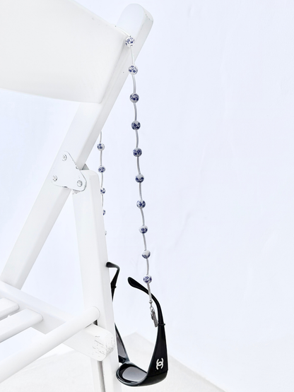 Pure Bloom handcrafted eyewear chain featuring silver bars and blue-and-white floral ceramic beads.