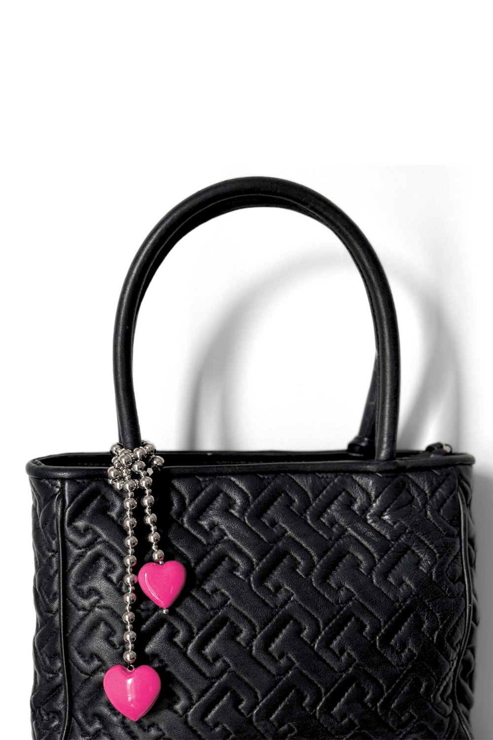 Pink hearts beaded bag charm on black bag.