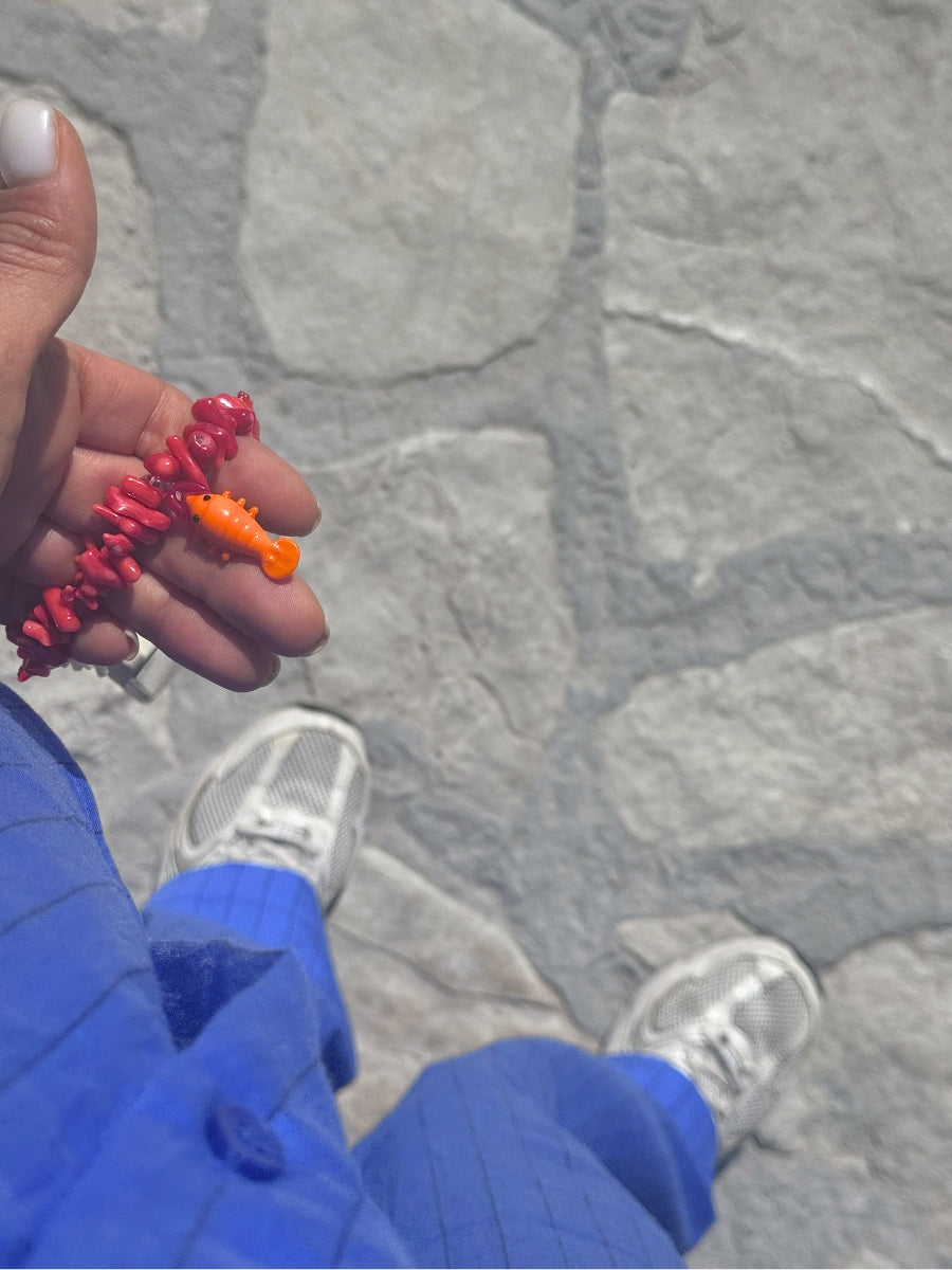 Handmade coastal-inspired phone strap shown in hand for size reference