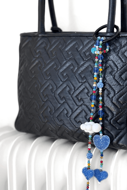Blue heart crystal beaded bag charm hanging on black purse.