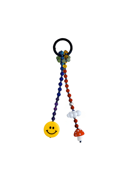 Detailed close-up of yellow smiley face, red mushroom, and cloud charm on beaded keychain.