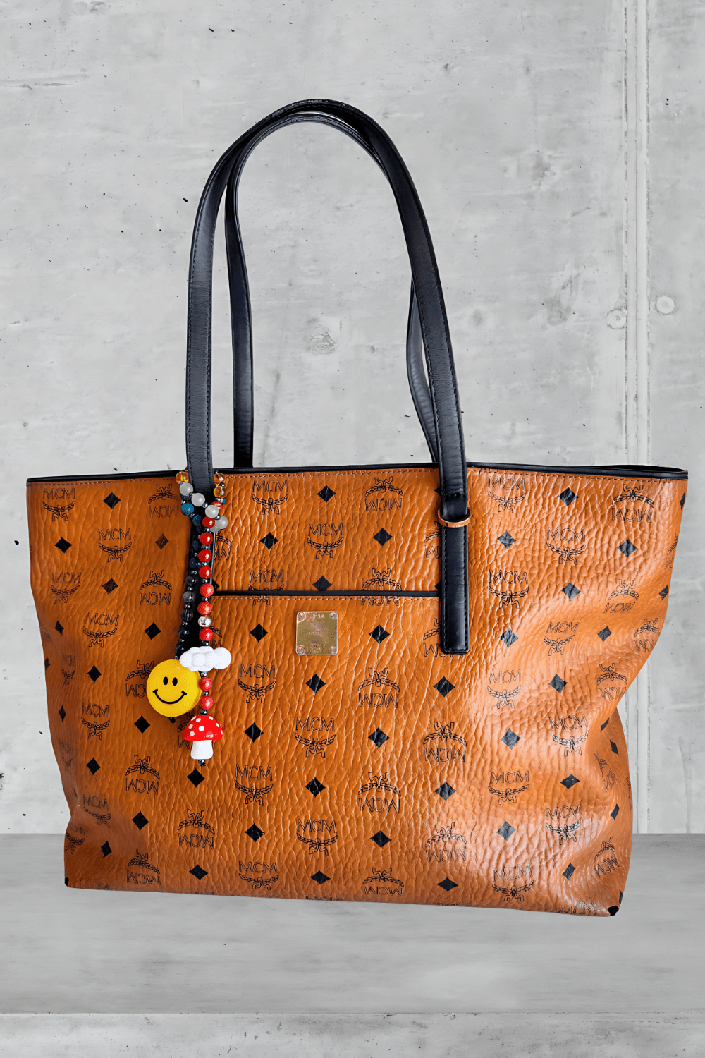 Colorful beaded bag charm attached to luxury brown MCM handbag handle.