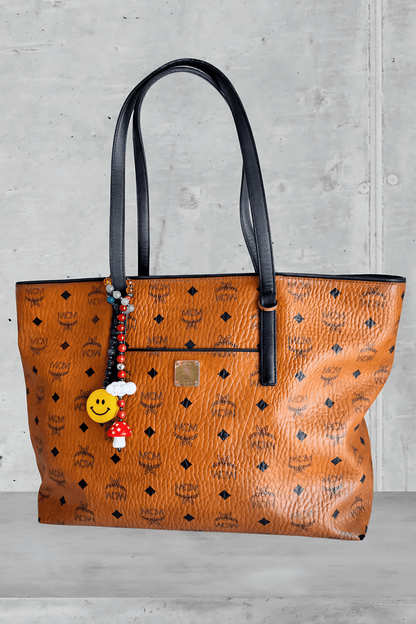 Colorful beaded bag charm attached to luxury brown MCM handbag handle.