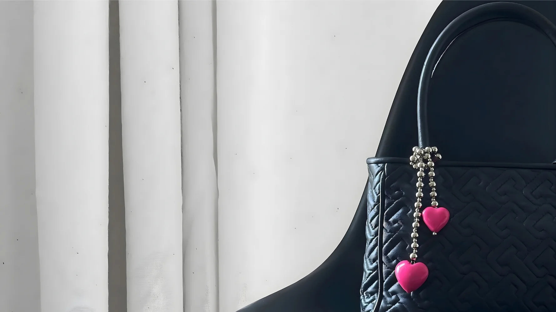 Black quilted handbag styled with pink heart bag charm by SPECSET — playful luxury accessory.