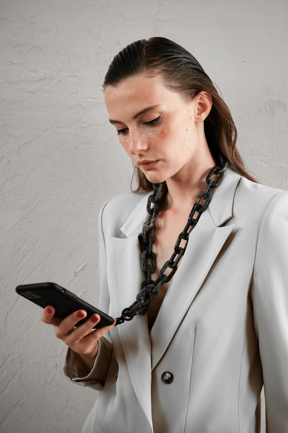 Model wearing the STATELY Chunky Gray Tortoise Phone Chain attached on a black phone case.